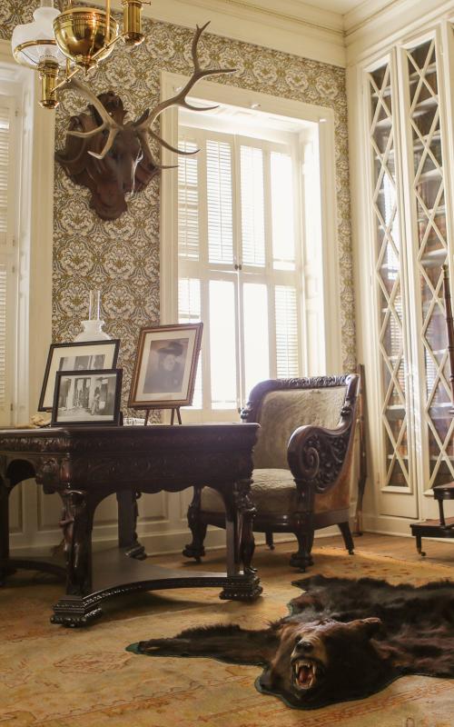 Elegant vintage study with deer head, bear rug, and antique chairs.